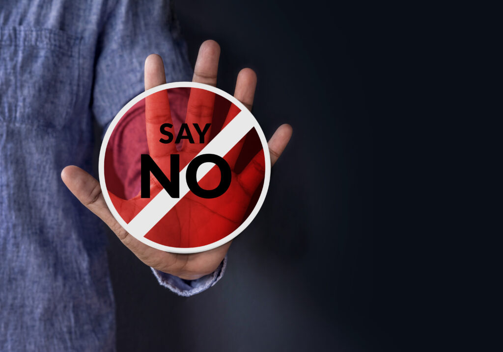 Ausgestreckte Hand. Auf der Handfläche ist ein Durchfahrt-verboten-Schild mit dem Text: Nein sagen